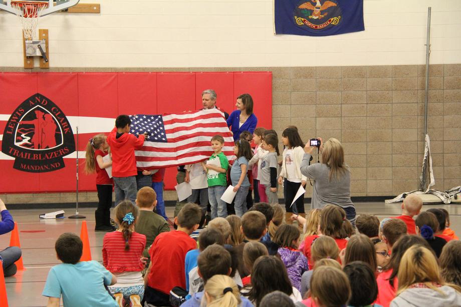 Lewis and Clark Elementary Flag Presentation-April 2015 - Hoeven visits Lewis and Clark Elementary School to present a U.S. flag to Melanie Campbell's first glade class and to speak at an assembly with the entire student body. In March, Ms. Campbell's students sent Hoeven letters requesting a flag to be flown over the U.S. Capitol, and he surprised the kids by delivering that flag during a school assembly about American history and traditions.